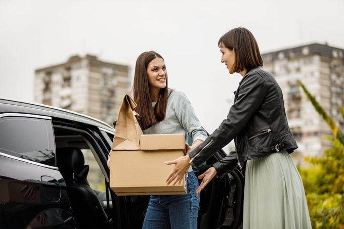 A woman loading her car with boxes and the other woman asking to help