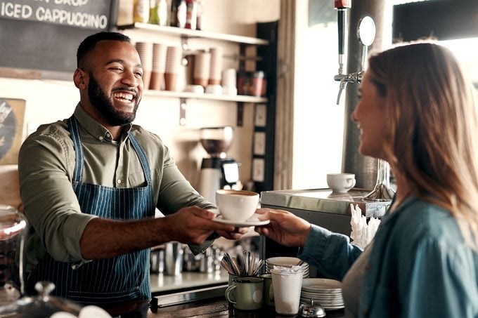 Smiling barista handing over coffee to customer