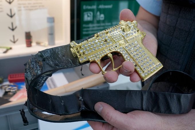 tsa agent holding a gold gun at an airport