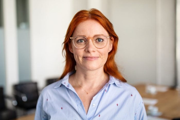 Portrait of confident mature businesswoman with red hair and blue eyes