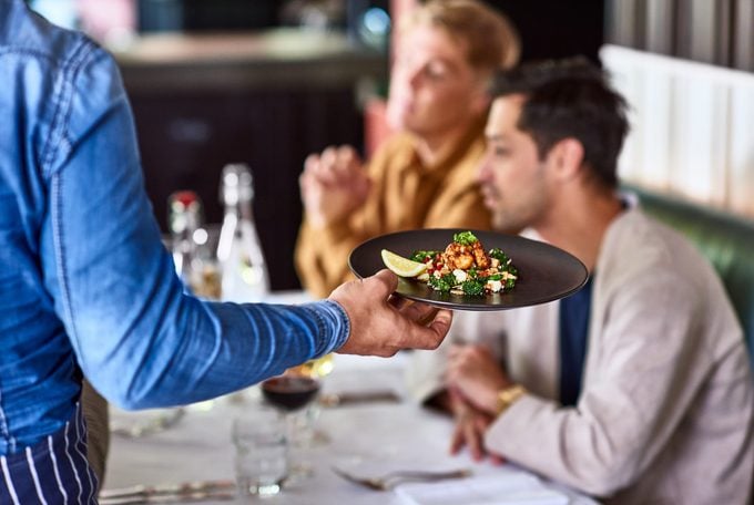 Waiter serving plate of food to customers