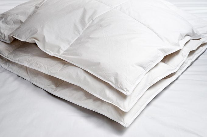 white down comforter folded on a bed