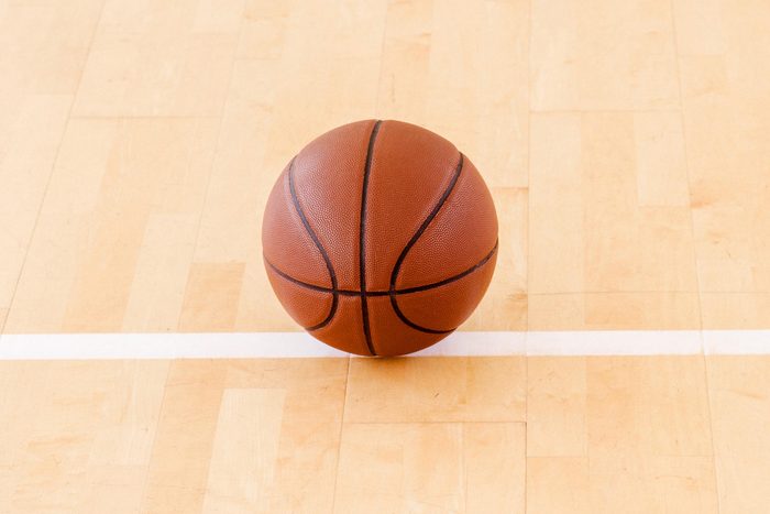 Basketball on hardwood court floor with natural lighting