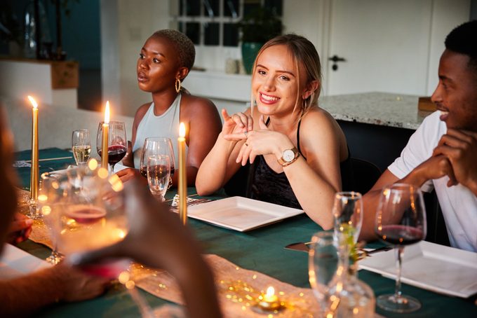 Young woman smiling while talking with friends during a dinner party