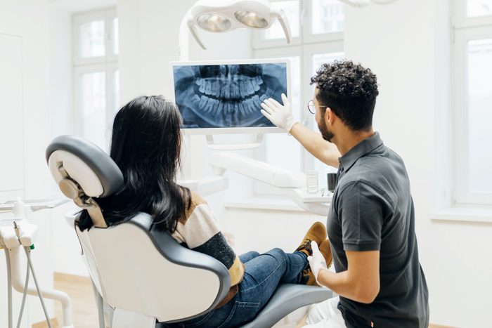 Dentist Showing Patient X-Ray Of Teeth After Check Up