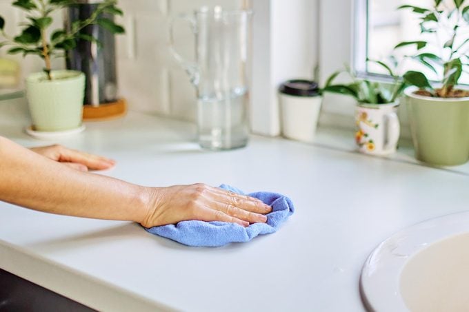 cleaning a kitchen counter with homemade multi purpose cleaner and a microfiber cloth