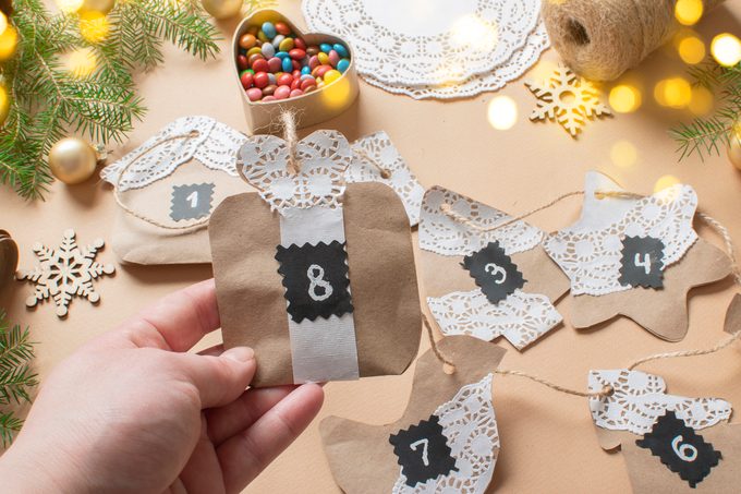 Christmas DIY with your own hands. In the hands of the Advent calendar is made of kraft paper using openwork napkins.