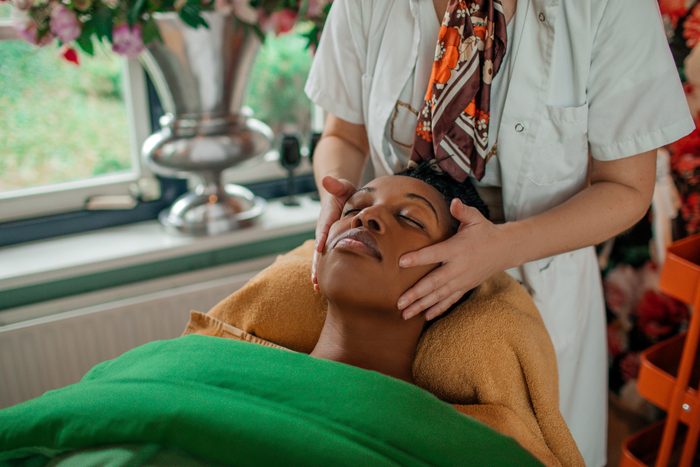 Facial massage by professional woman for beautiful black woman