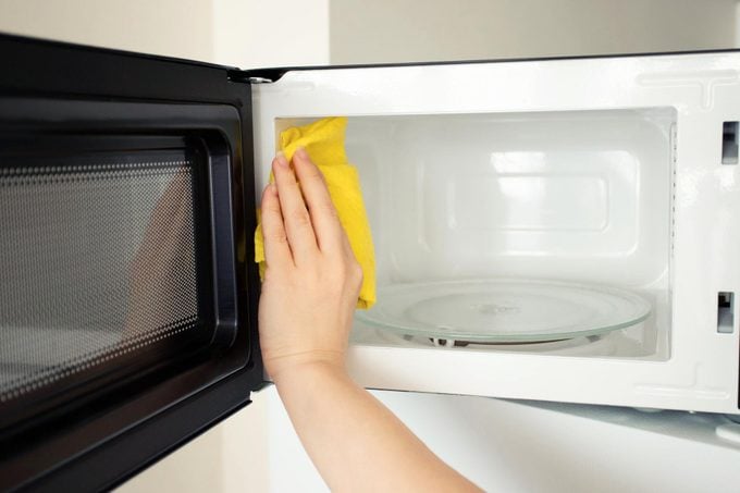 cleaning a microwave with a yellow microfiber cloth an natural homemade cleaner