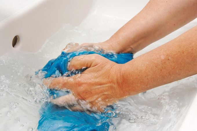 hands soaking blue shirt in a sink