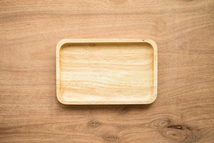 Top view of unused new brown handmade wooden dish plate on wooden table background.