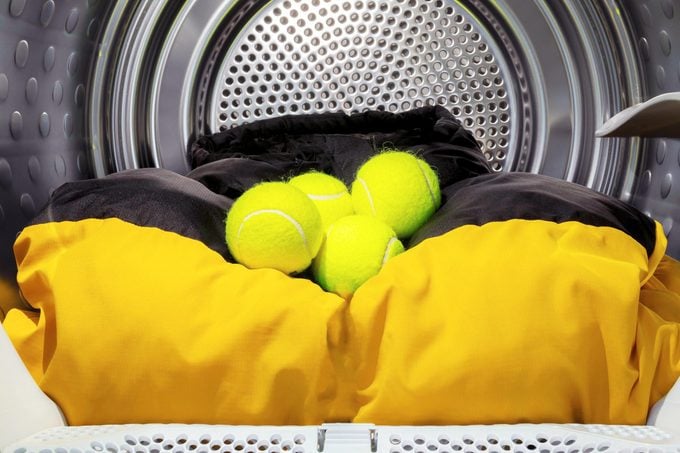 tennis balls in dryer with black and yellow comforter