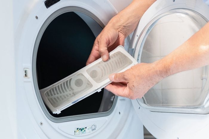 A person cleaning the lint of a dryer