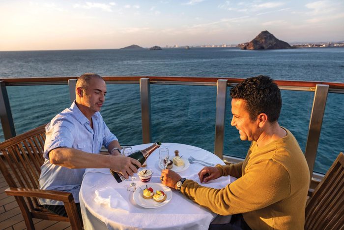 two men on a cruise enjoying dinner on a deck