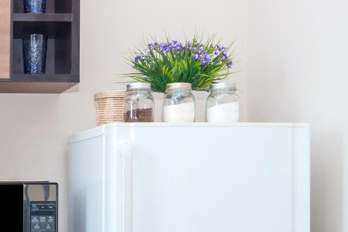 jars and plants on top of white fridge in an organized kitchen