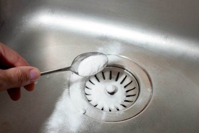 cleaning kitchen sink with baking soda on a spoon
