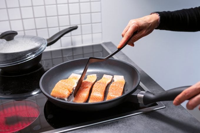 cooking salmon in a pan on the stove