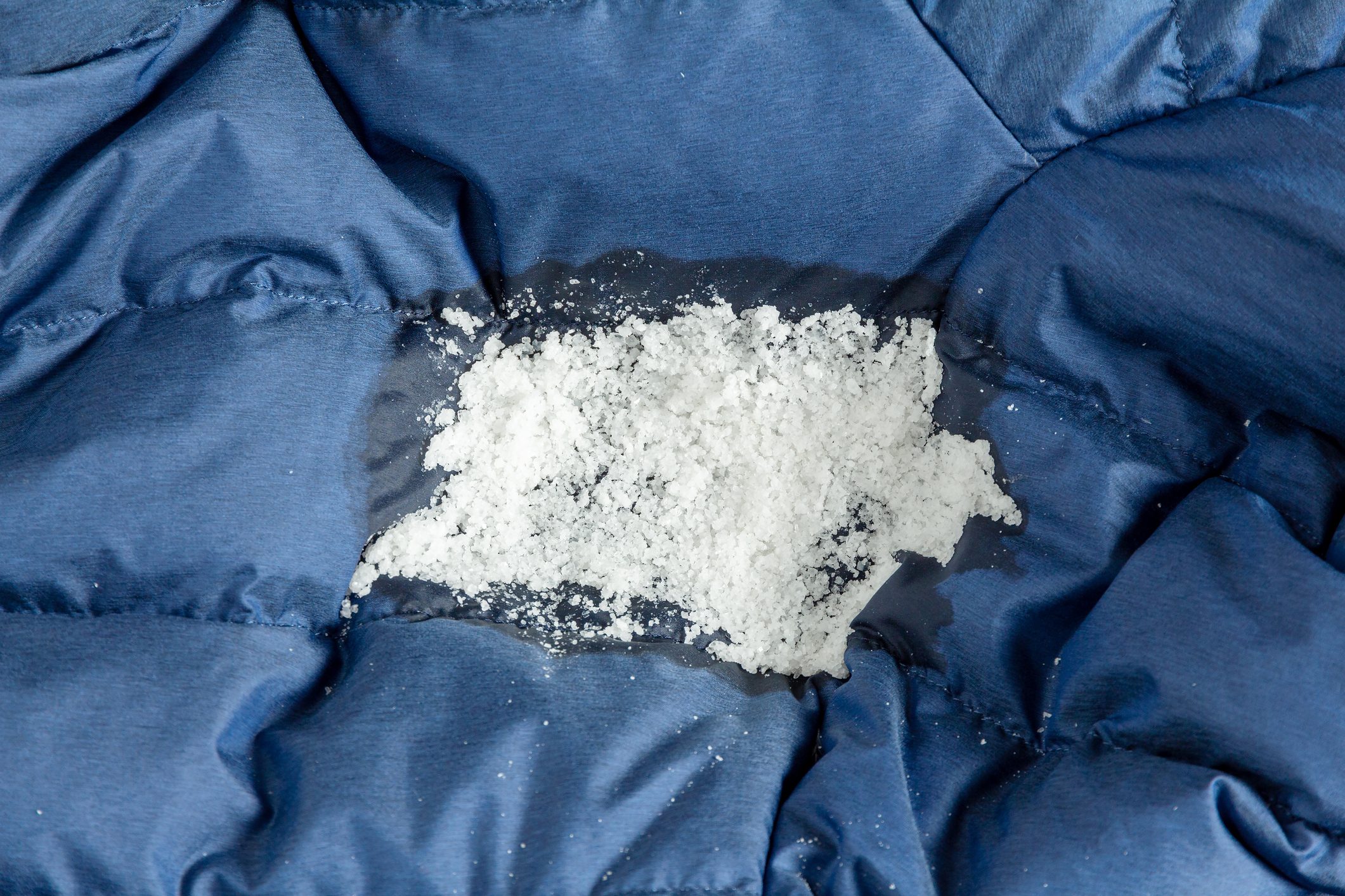 Crystals of edible salt on the fabric of a jacket to remove dirty oil stains