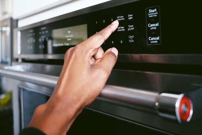 woman pressing the self cleaning oven button