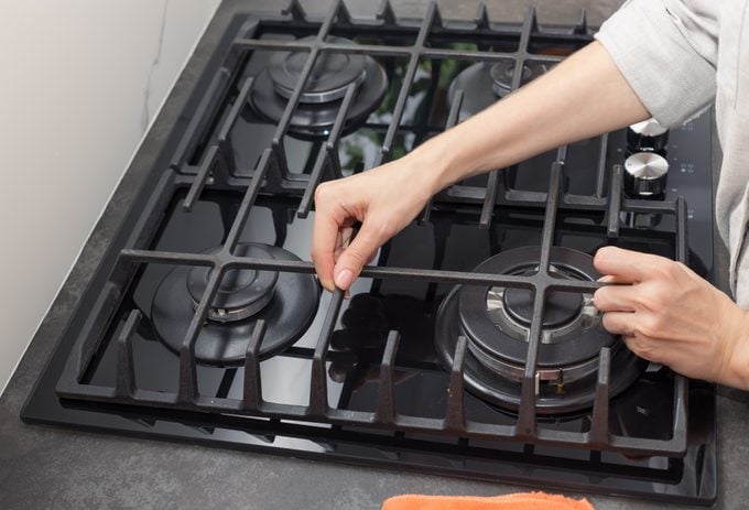 dirty gas stove top. woman preparing to clean kitchen