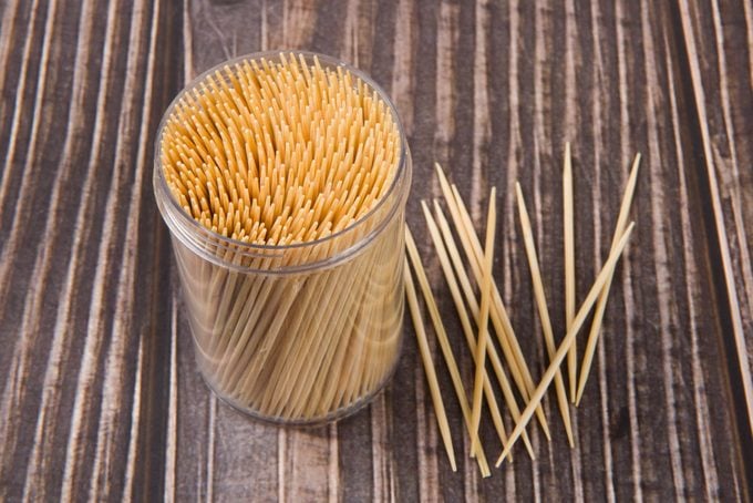 Wooden toothpicks and holder on wood background