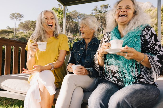 Senior friends laughing happily while having tea