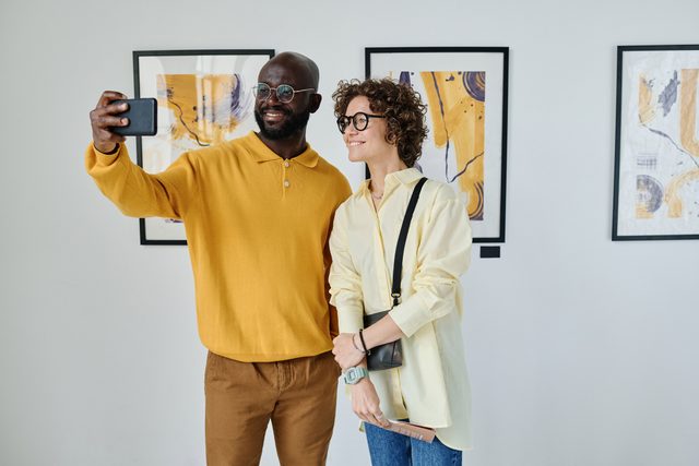 Young couple taking selfie at art gallery