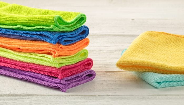 Stack of kitchen microfiber towels in bright colors on a white wooden background