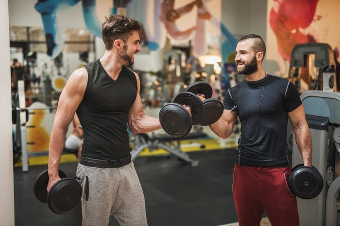 Two muscular build men having weight training in a gym.