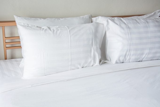 white pillow on bed with white blanket in bedroom