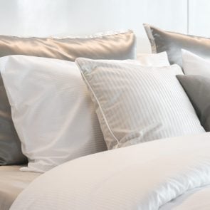 Gray color scheme pillows setting on bed with satin finished style bedding