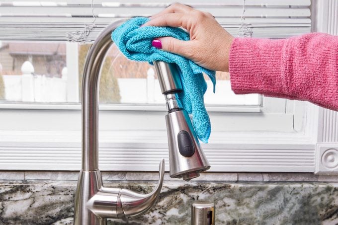 using microfiber cloth to wipe faucet head