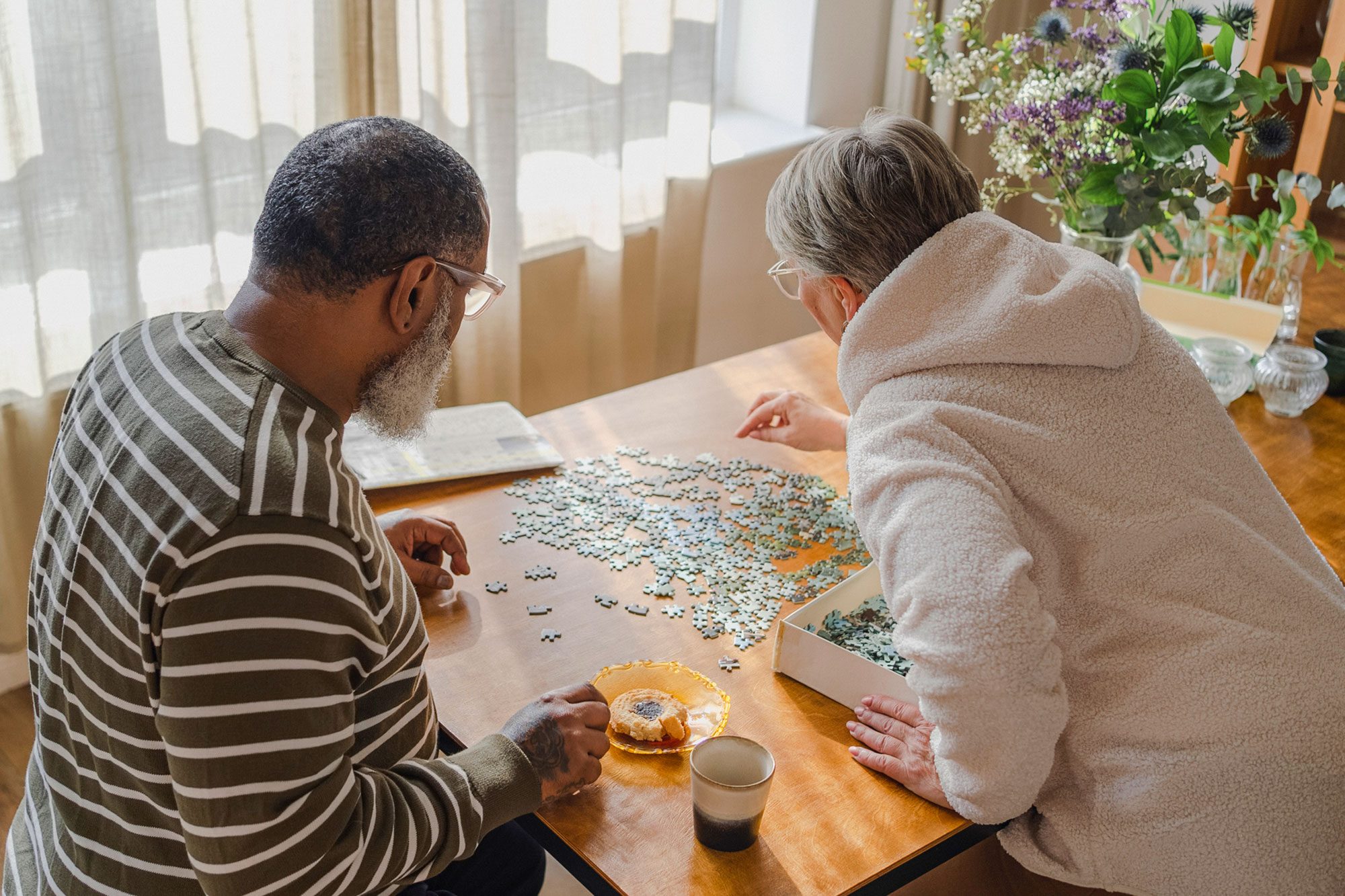 Senior Couple Doing Jigsaw Puzzle On Table At Home