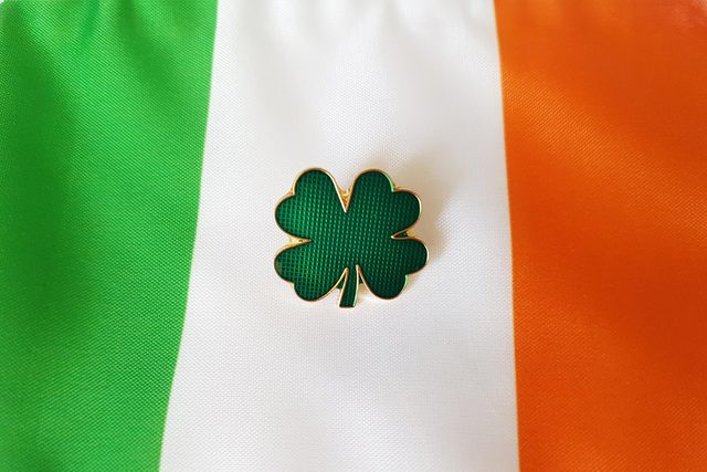green four leaf clover pin resting on Irish flag