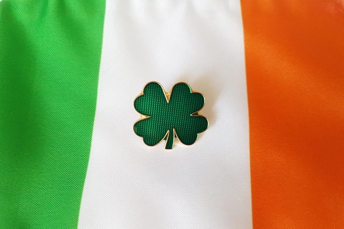 green four leaf clover pin resting on Irish flag