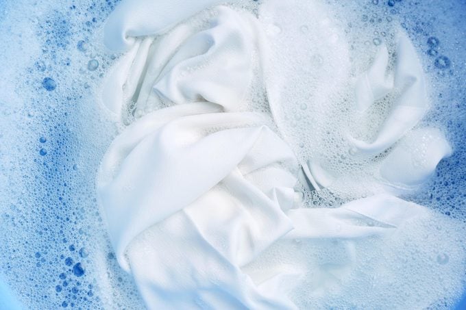 white shirt submerged in soapy detergent water
