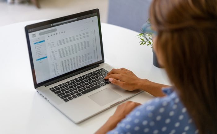 Woman working at home and reading e-mails on her laptop