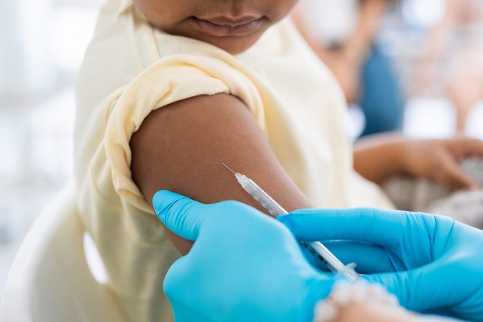 Immunisation. Protecting children from diseases. Close-up nurse in medical gloves giving injection to little patient. Brave boy getting a flu shot at doctor's office and looking at needle
