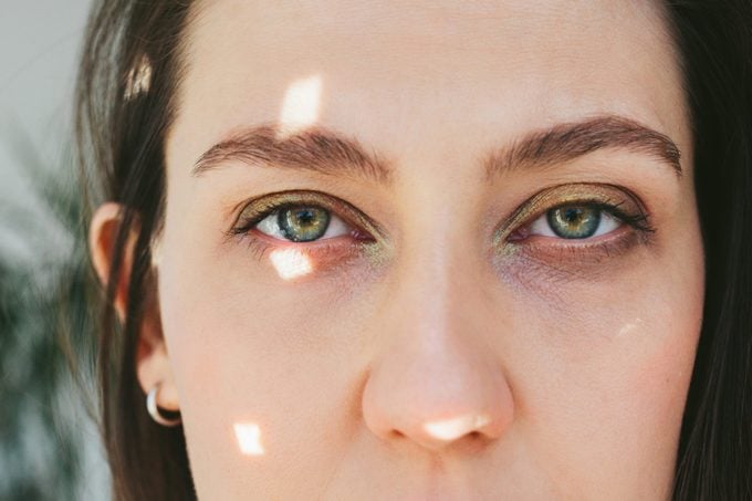 Close up portrait of young woman with green eyes, sun glare