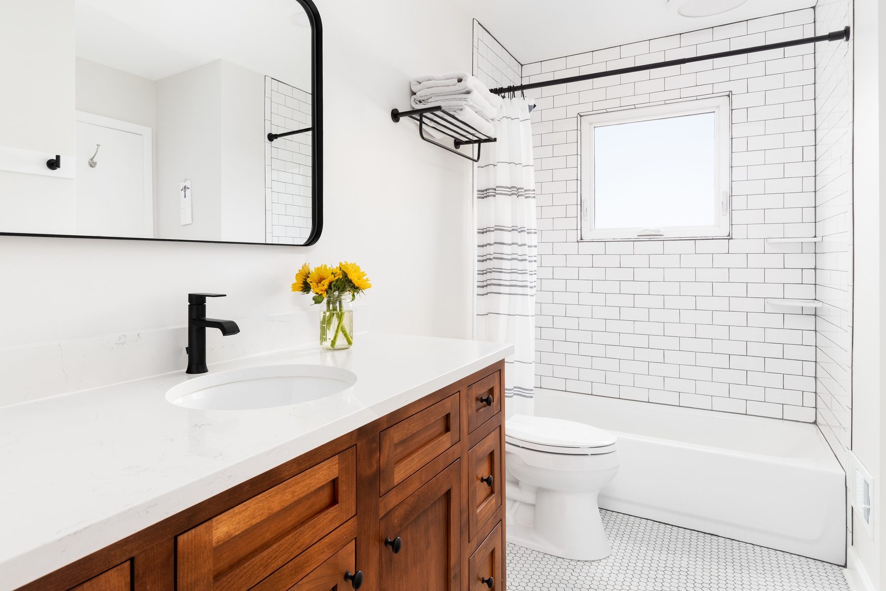 A farmhouse bathroom with a wood cabinet and subway tile shower.