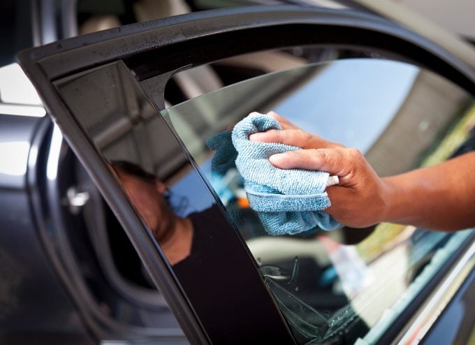 cleaning car window with blue microfiber cloth