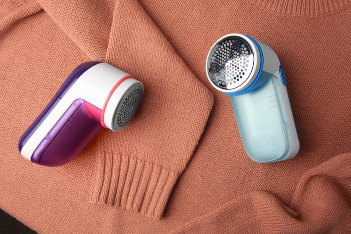 Modern fabric shaver on sweater with lint, flat lay