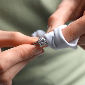 Jeweler cleaning diamond ring with microfiber cloth, closeup