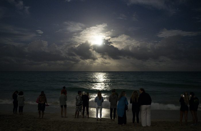 People gather on the beach to watch the full moon in Miami Beach, Florida on January 25, 2024. (Photo by CHANDAN KHANNA / AFP) (Photo by CHANDAN KHANNA/AFP via Getty Images)