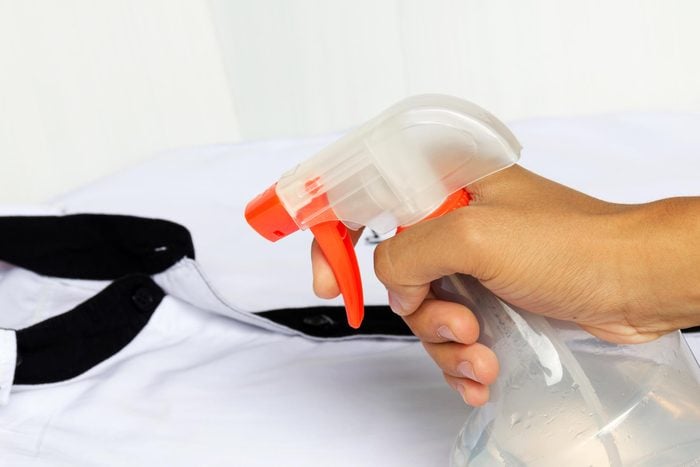 spraying clothes with spray to get rid of wrinkles
