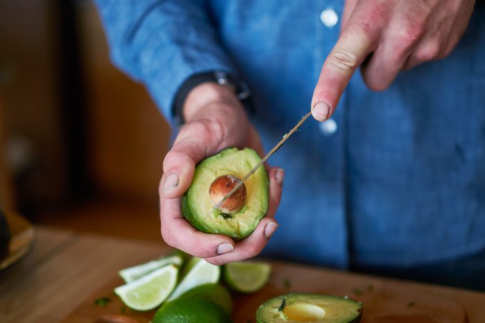 man cutting avocado to use in making guacamole close up