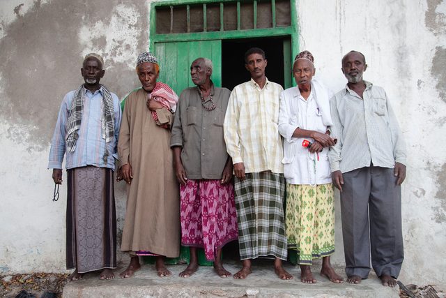 Group of village men standing in front of a door