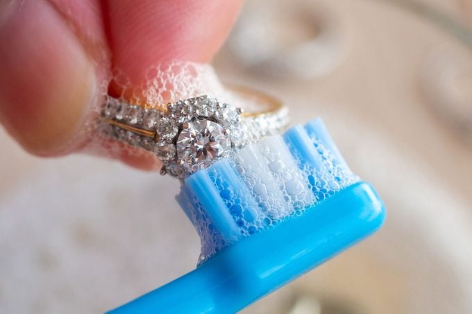 Hand Cleaning diamond ring with baby toothbrush close up