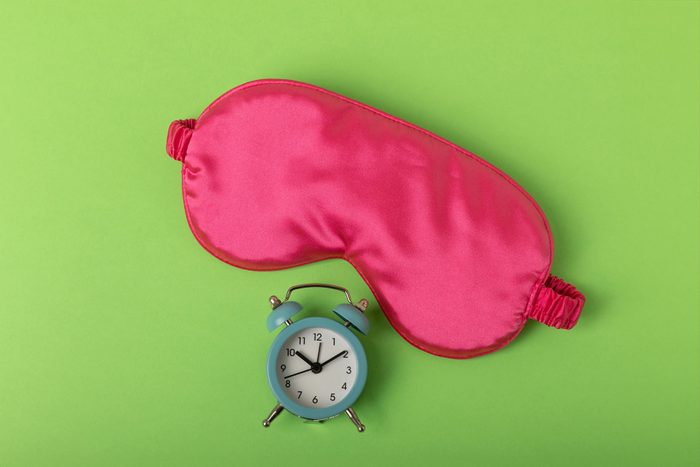 Pink Sleeping Mask and Small Clock on Green Background