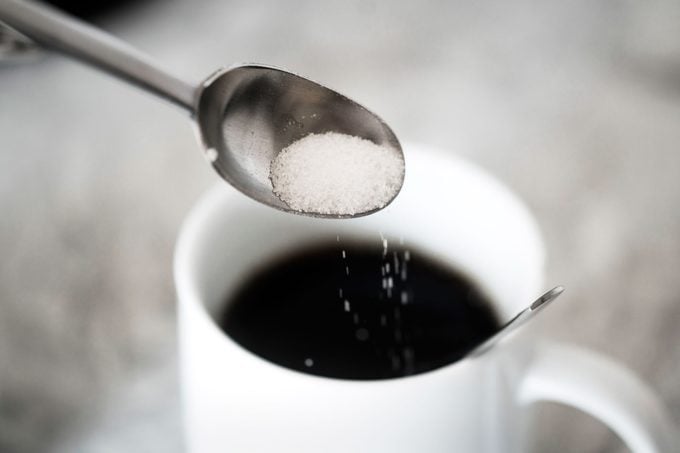 salt on spoon going into black coffee